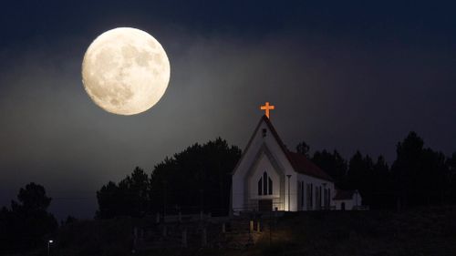 A larger-than-normal moon appears alongside a church in Portugal's north. (AAP)