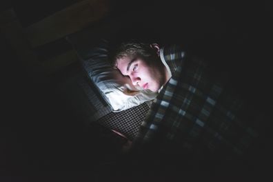 Teenager on his phone in bed
