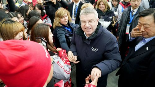 IOC President Thomas Bach is welcomed by volunteer workers in Pyeongchang. There are rising tensions between North and South Korea amid planned unity events. (AAP)