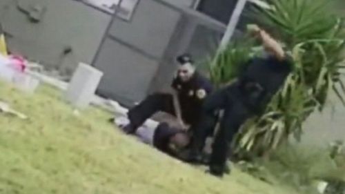 One officer then approaches him, and as he finishes handcuffing him, another officer runs up and appears to kick the prone suspect. (ABC News US)