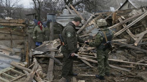 Ukraine soldiers and a woman inspect the damage from recent shelling. (AAP)