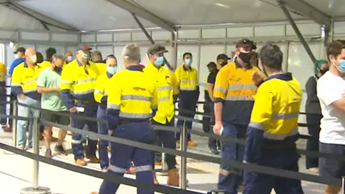 Workers line up at the Rio Tinto testing facility at Perth Airport to get RATs. 