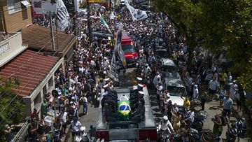 The casket of late Brazilian soccer great Pele is draped in the Brazilian and Santos FC soccer club flags as his remains are transported from Vila Belmiro stadium, where he laid in state, to the cemetery during his funeral procession in Santos, Brazil, Tuesday, Jan. 3, 2023.