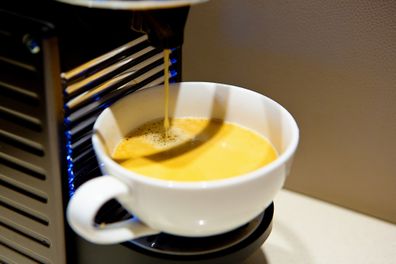 Brewed coffee trickles down from a coffee maker of the type that uses pre-packaged capsules.