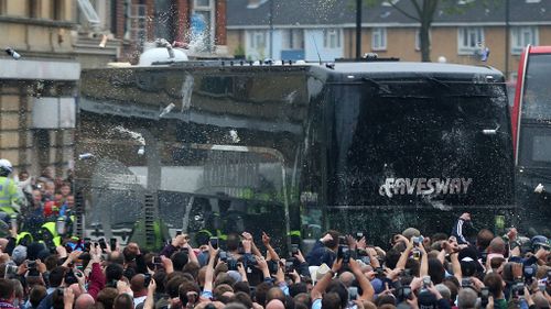 Fans congregate in the street and throw bottles and cans at the Manchester United team bus prior to the match. (Getty)