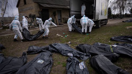 Des volontaires chargent les corps de civils tués à Bucha dans un camion pour les emmener à une morgue pour enquête, dans la périphérie de Kiev, en Ukraine, le mardi 12 avril 2022. 