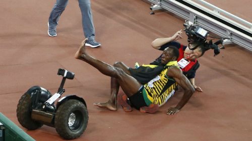 Usain Bolt and a cameraman fall to the found at the Bird's Nest in Beijing.