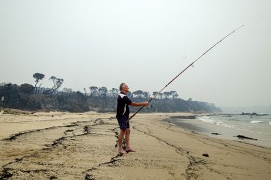 Brett Mayor ,59, from Frankston fishes from the shore in Mallacoota on January 15, 2020 , Australia. 