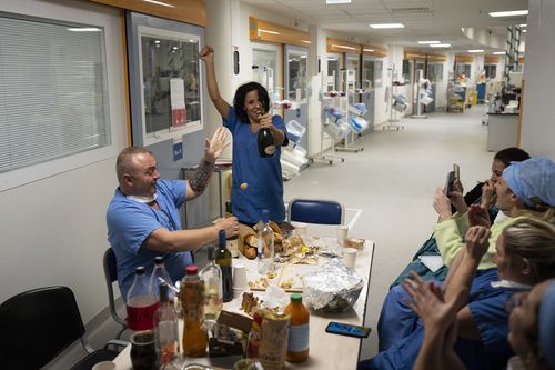 Nurse Bess Tribout, center, pops champagne to celebrate the new year in the COVID-19 intensive care unit at the la Timone hospital in Marseille, southern France, Saturday, Jan. 1, 2022. 