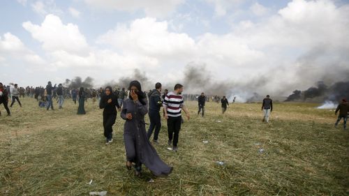 Palestinian protesters run to cover from teargas fired by Israeli soldiers during clashes with Israeli troops along the Gaza Strip border with Israel, east of Khan Younis. (AP)