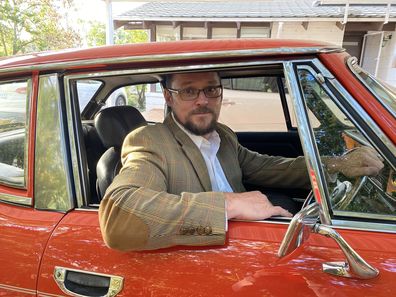 Andrew poses in a classic car Jen gifted him for their 20th wedding anniversary.