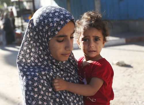 Palestinians flee their homes in the Shajaiyeh neighborhood of Gaza City, after Israel had airdropped leaflets warning people to leave the area, Wednesday, July 16, 2014. (AAP)