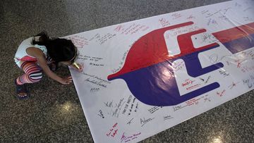A young girl writes a message for the passengers of missing Malaysia Airlines flight MH370 at Kuala Lumpur International Airport (MOHD RASFAN/AFP/Getty Images)