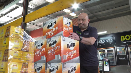 Orange Cellars manager George Eleftheriou stacking cartons of beer before his next customer arrives.