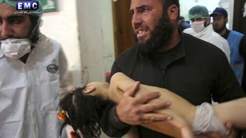 A man carries a child injured in the attack. (Edlib Media Centre via AAP)