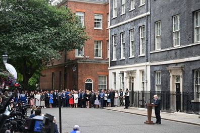 Prime Minister Boris Johnson addresses the nation as he announces his resignation outside 10 Downing Street watched by wife Carrie Johnson (in red) fellow MPs and staff on July 7, 2022 in London, England. 