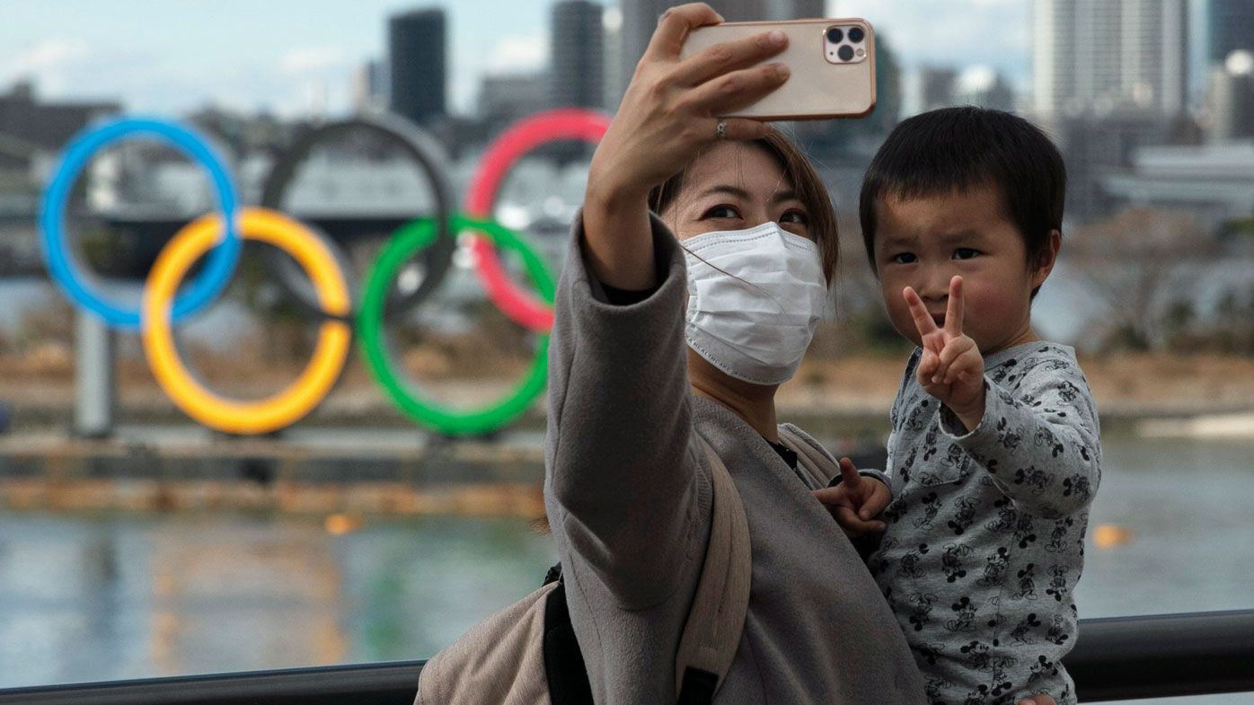 A woman with a young boy takes a selfie with the Olympic rings, in Tokyo&#x27;s Odaiba district.