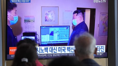 People watch a TV screen showing a file image of North Korean leader Kim Jong Un, right, during a news program at a train station in Seoul, South Korea,