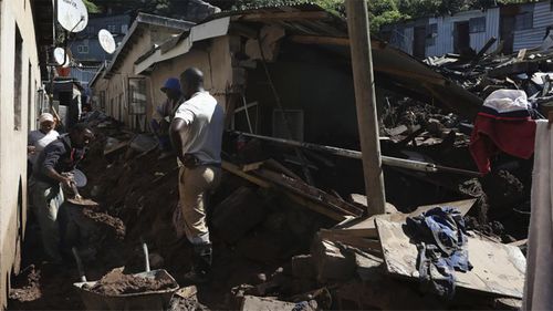 People clear mud from damaged houses following floods, at Clermont in Durban, South Africa, Thursday, April 14, 2022.