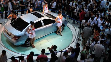 Visitors to a car fair look at a BYD car 