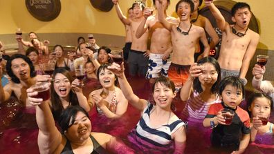 Japanese bathhouse guests celebrate the release of  France’s Beaujolais Nouveau 2014 wine in a 'wine bath' party that is held over 10 days. (AAP)