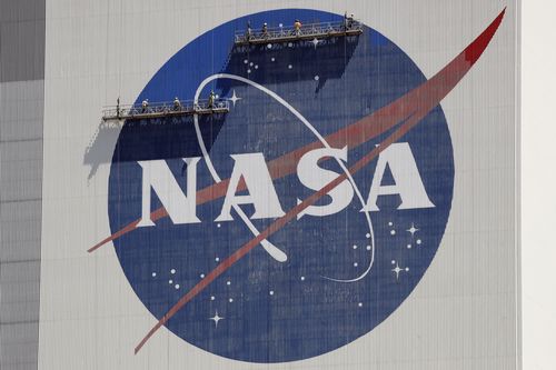 Workers on scaffolding repaint the NASA logo near the top of the Vehicle Assembly Building at the Kennedy Space Center in Cape Canaveral, Fla., Wednesday, May 20, 2020. On Thursday, June 9, 2022, NASA announced it is launching a study of UFOs as part of a new push toward high-risk, high-impact science, setting up an independent team to see how much information is publicly available on the matter and how much more is needed. (AP Photo/John Raoux, File)
