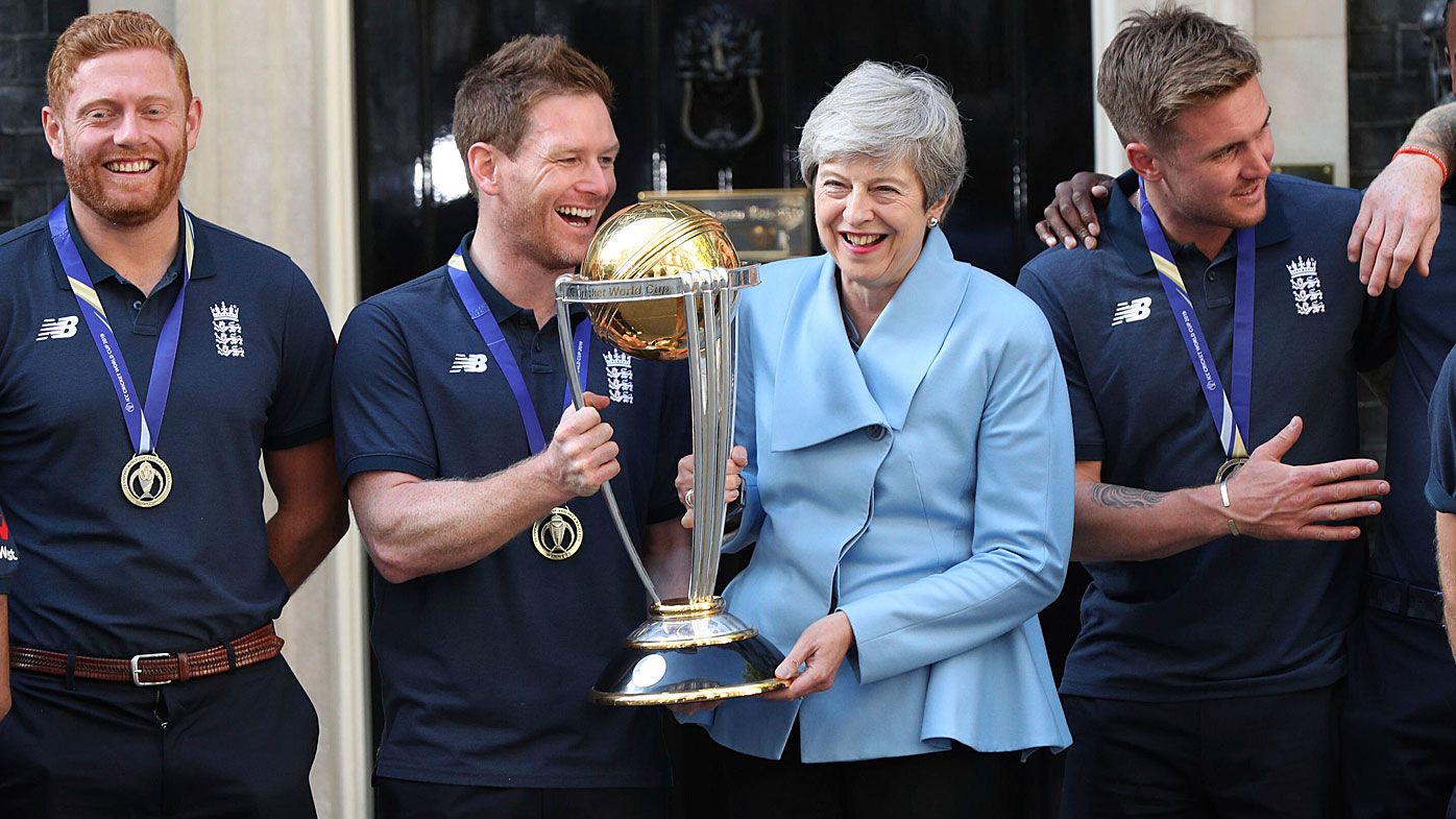 Britain's Prime Minister Theresa May smiles as she stands with England cricket captain Eoin Morgan, members of the team and the trophy