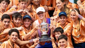 Iga Swiatek of Poland poses among ball kids with the champions trophy after defeating Jasmine Paolini of Italy in the womens singles final on Day 14 of the French Open at Roland Garros on June 08, 2024 in Paris, France (Photo by Robert Prange/Getty Images)