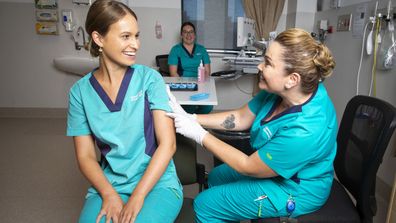 Registered Nurse Zoe Park receives the first COVID-19 vaccine from clinical nurse consultant Kellie Kenway at Gold Coast University Hospital.