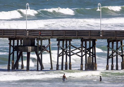 Beachgoers play in high surf next to the Main Street Pier in Daytona Beach, Florida. Hurricane Dorian, a powerful Category 5 storm, is expected to pass over The Bahamas before heading to the east of Florida on the upcoming week.