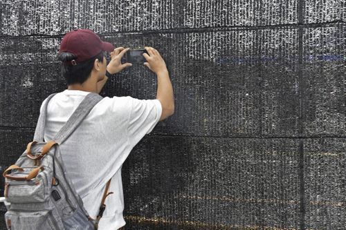 A visitor tries to take a photo through a hole on a black screen in Fujikawaguchiko town