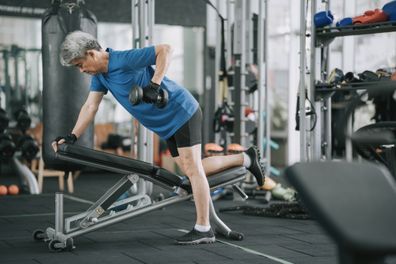 Asian Chinese Senior Man workout with dumbbell in gym