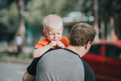 Crying boy on dad's shoulder