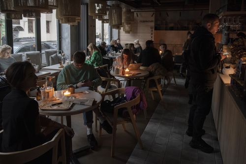 People sit in a cafe during a blackout in Kyiv, Ukraine, Thursday, Nov. 3, 2022.
