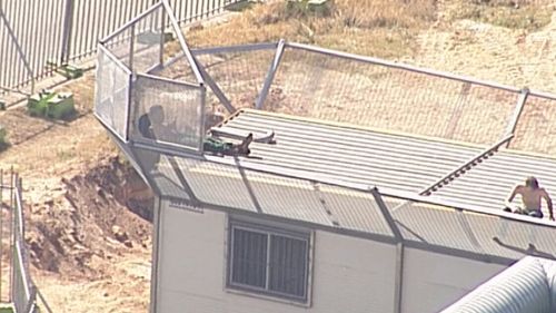 The young men have been seen throwing objects from the roof of Brisbane Youth Detention Centre. (9NEWS)