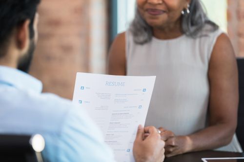A businessman reads a resume during a job interview with a potential employee.