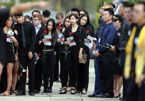 Mourners hold flowers during the funeral for Peter Wang. (AAP)