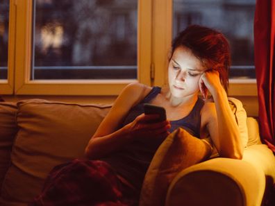 Woman at home alone texting on her phone.