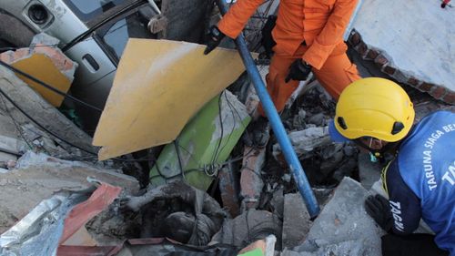 A survivor is pulled from the wreckage after the earthquake and tsunami in Indonesia which has killed hundreds of people.