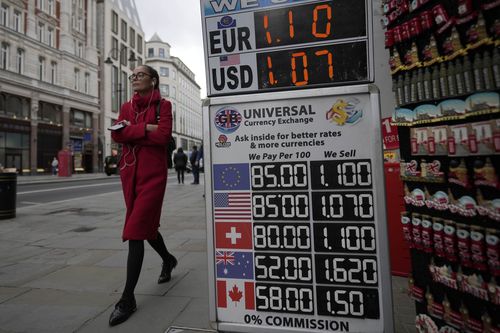 A woman walks past a sign that shows the exchange rate at a bureau de change in London, Tuesday, September 27, 2022. 