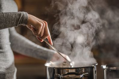 Unrecognizable woman stirring soup in a saucepan while making lunch. Cooking.