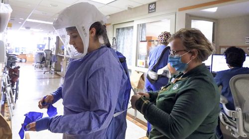 دب دالسینگ ، مدیر پرستار واحد درمان COVID-19 در UW Health به کمک پرستار Ainsley Billesbach با تجهیزات حفاظت شخصی خود در بیمارستان در مدیسون ، ویسکانسین (عکس: 5 نوامبر 2020)