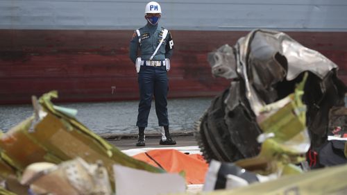 An Indonesian soldier stands guard near debris found in the waters around the site where a Sriwijaya Air passenger plane crashed into the search and rescue command center at Tanjung Priok port in Jakarta, Indonesia, Friday, 15 January 2021