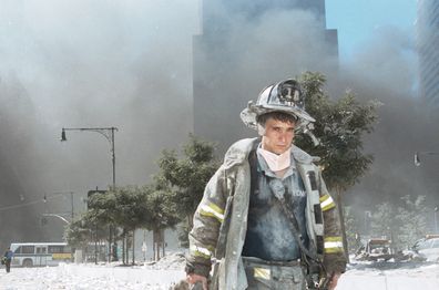 Covered in dust and with smoke in the distance, an unidentified New York City firefighter walks away from Ground Zero after the collapse of the Twin Towers on September 11, 2001.