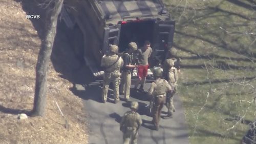 This image made from video provided by WCVB-TV, shows Jack Teixeira, in T-shirt and shorts, being taken into custody by armed tactical agents on Thursday, April 13, 2023, in Dighton, Massachusetts