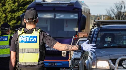 Victoria Police members stop motorists leaving metropolitan Melbourne at a checkpoint set up on the on the Calder Freeway 