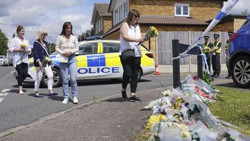 Family friend Lea Holloway, left, arrives with others to place tributes following the deaths of three women who were killed in an attack at their home, on Tuesday in Bushey, England, Thursday July 11, 2024.  