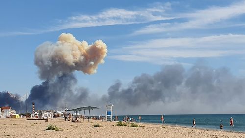 Rising smoke can be seen from the beach at Saky after explosions were heard from the direction of a Russian military airbase near Novofedorivka, Crimea, Tuesday Aug. 9, 2022. The explosion of munitions caused a fire at a military air base in Russian-annexed Crimea Tuesday but no casualties or damage to stationed warplanes, Russia's Defense Ministry said. (UGC via AP)