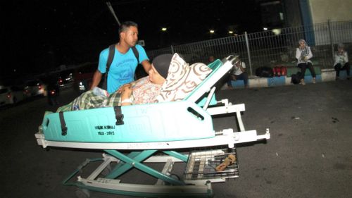 A man pushes a relative who lies on a hospital bed as they were told to get to higher ground in Pedang.