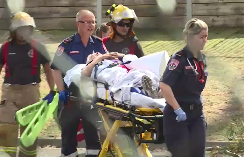 The injured teacher is stretchered away from the school after being freed. (9NEWS)